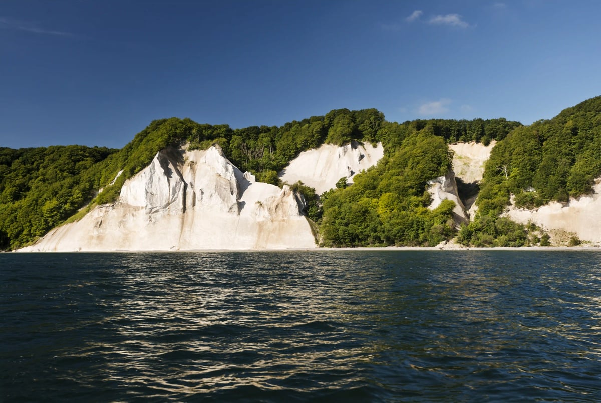 Weisse Kreidefelsen der Insel Møn an der Ostsee, umgeben von dichtem grünen Wald.