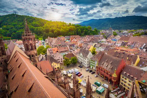 Blick über die historische Altstadt von Freiburg mit Münsterturm, bunten Häusern und belebtem Marktplatz