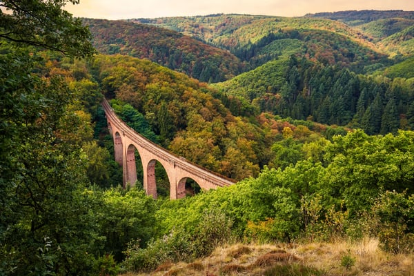 Historischer Eisenbahnviadukt der Hunsrückbahn führt durch bewaldete Hügellandschaft im Herbst