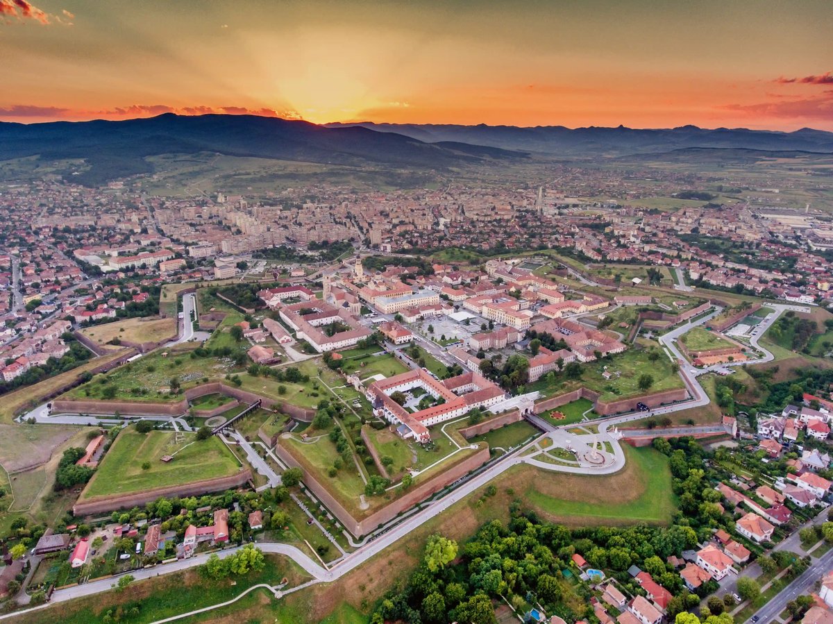 Luftaufnahme der sternförmigen Vauban-Festung Alba Iulia bei Sonnenuntergang, Bastionen und Stadt bis zu den Bergen