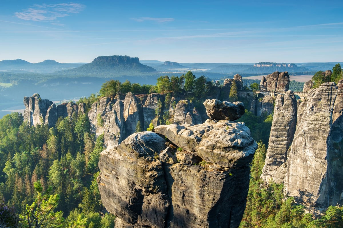 Vue panoramique sur les formations rocheuses de grès de la Suisse saxonne avec plateaux boises et vallees profondes a la lumiere du matin