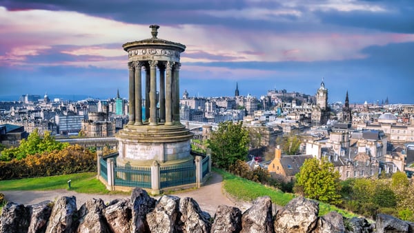 Panoramablick über Edinburgh mit klassischem Denkmal auf einem Huegel und Stadtlandschaft im Hintergrund