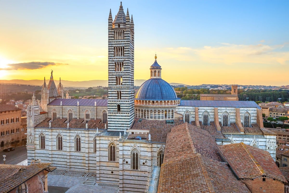 Blick auf den Dom von Siena mit charakteristischer Kuppel und Glockenturm bei warmem Abendlicht