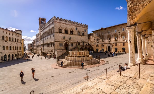 Historischer Marktplatz in Perugia mit Brunnen, mittelalterlichen Gebäuden und Menschen bei sonnigem Wetter
