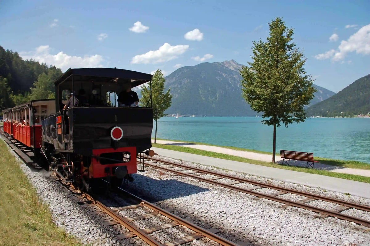 Train historique à vapeur à crémaillère au bord de l’Achensee, avec les montagnes du Tyrol en arrière-plan.