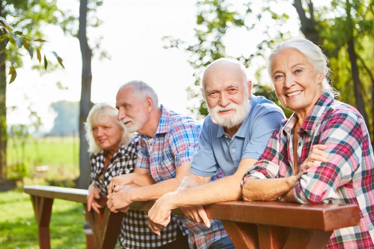 Quatre voyageurs seniors profitent ensemble d’un moment dans la nature.