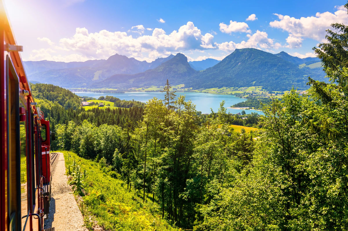 Rote Schafbergbahn in der Berglandschaft des Salzkammerguts mit Blick auf den Wolfgangsee.