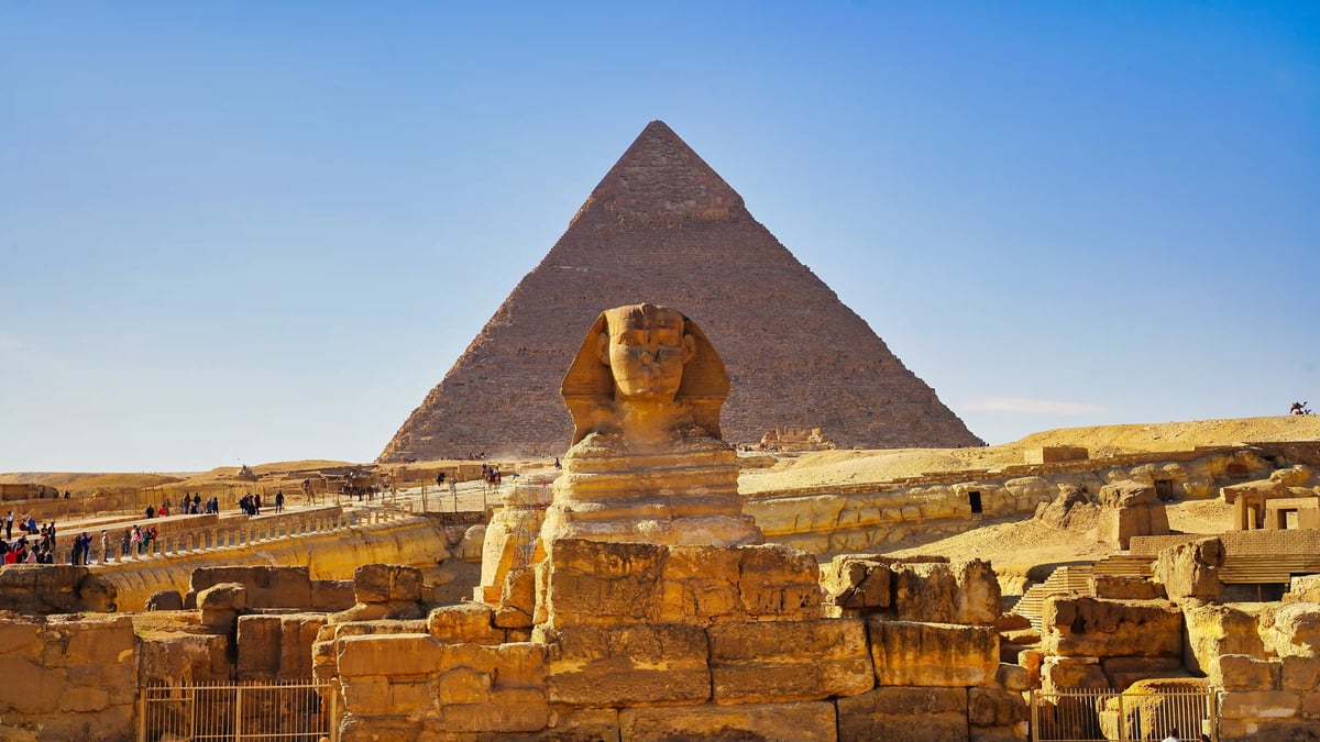 Sphinx von Gizeh mit einer grossen Pyramide im Hintergrund in der ägyptischen Wüste