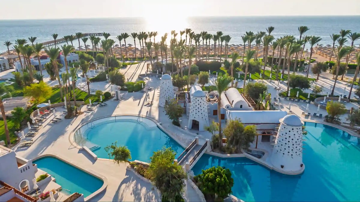 Weitläufige Hotelanlage mit mehreren Pools, Palmen, Sonnenterrassen und direktem Zugang zum Strand am Roten Meer
