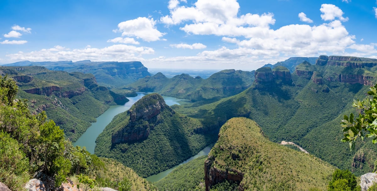 Weitläufiger Blick auf den Blyde River Canyon mit gewundenem Fluss, steilen Felsformationen und dichter Vegetation