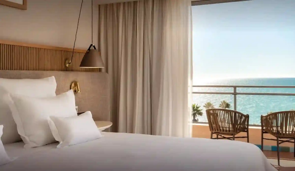 Helles Hotelzimmer mit grossem Bett und Balkon mit Blick auf das blaue Meer