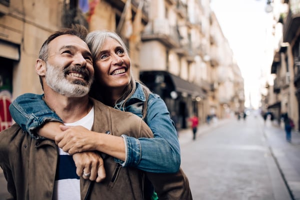 Reifer Mann und Frau umarmen sich lächelnd in einer schmalen Altstadtstrasse mit historischen Gebäuden
