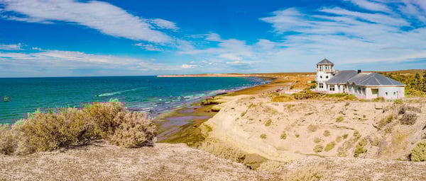 Küste bei Puerto Madryn mit Klippen, Strand und Gebäude am Meer