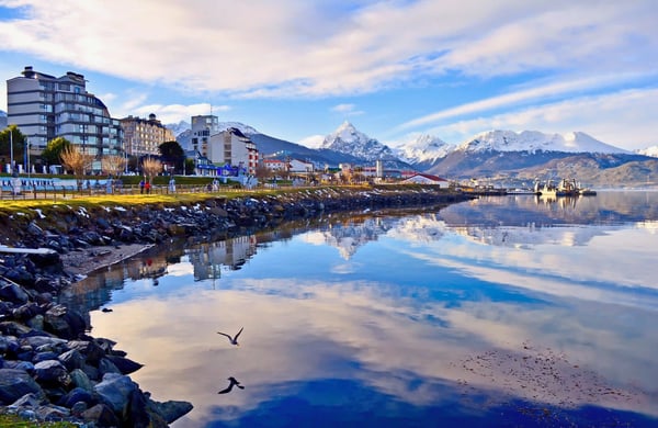 Stadt Ushuaia mit Bergen im Hintergrund und Spiegelung im ruhigen Wasser