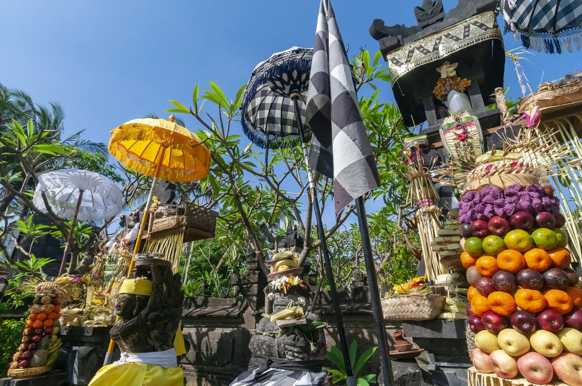 Balinesischer Schrein mit Opfergaben, Früchten, Sonnenschirmen und religiösen Symbolen