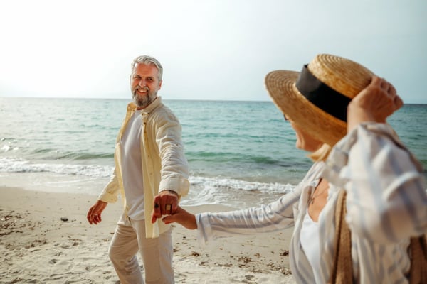 Paar geht Hand in Hand am Sandstrand entlang des Meeres