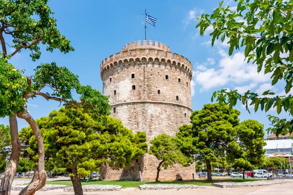 Weisser Turm von Thessaloniki umgeben von Bäumen unter blauem Himmel