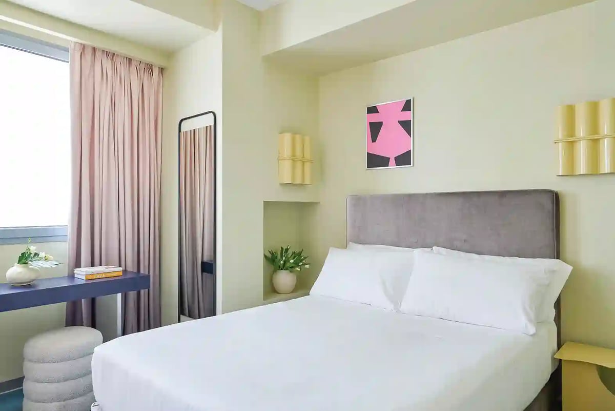 Modernes Hotelzimmer mit Doppelbett, hellem Interieur, Tisch und Fenster
