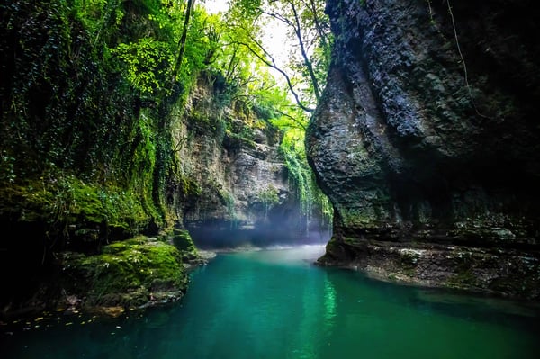 Tiefer, grüner Canyon in Georgien mit steilen Felswänden, klarem türkisfarbenem Wasser und üppiger Vegetation