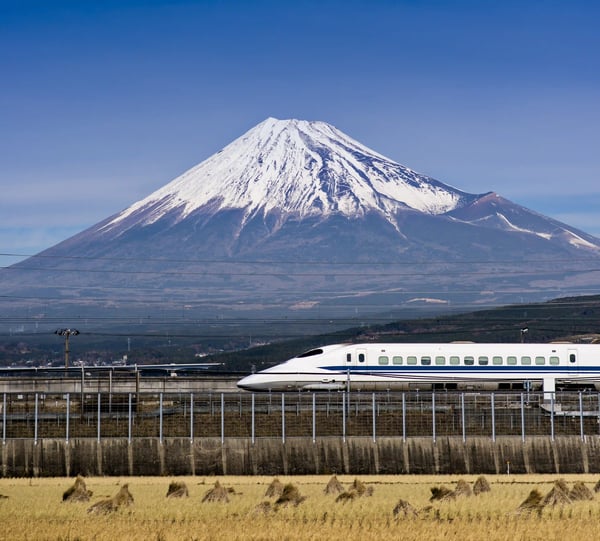 Shinkansen Hochgeschwindigkeitszug faehrt vor dem schneebedeckten Fuji Berg vorbei