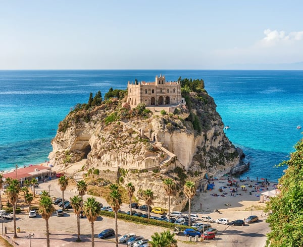 Kirche auf einem hohen Felsen über dem Meer bei Capo Vaticano, umgeben von Strand, Palmen und azurblauem Wasser
