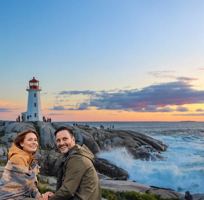 Paar sitzt auf Felsen an der kanadischen Atlantikküste, im Hintergrund ein weisser Leuchtturm, Meer und Abendhimmel mit Wolken
