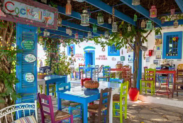 Traditionelle griechische Taverne mit bunten Tischen, Stühlen, Laternen und schattigem Innenhof