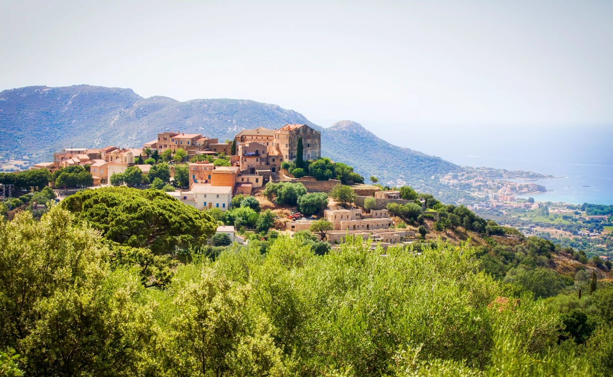 Historisches Bergdorf in der Balagne mit Steinhäusern, Olivenbäumen und Blick auf die Küste