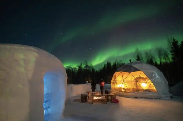 Beleuchtetes Glasiglu unter Nordlichtern in winterlicher Nacht