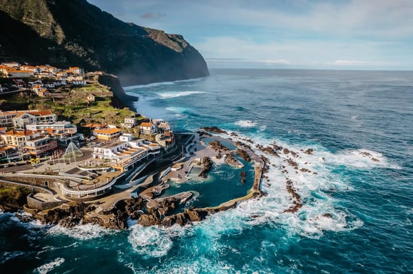 Village côtier de Porto Moniz avec piscines naturelles en roche volcanique, bateaux et falaises spectaculaires au bord de l’Atlantique