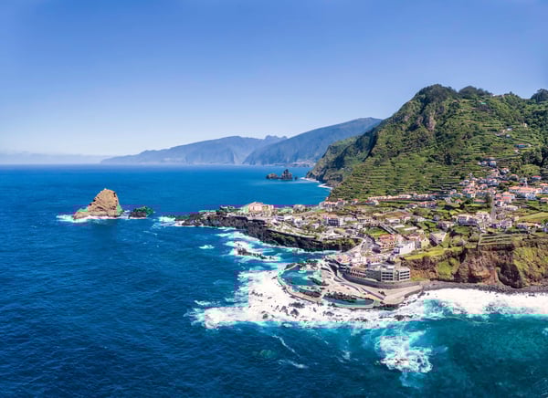 Village côtier de Porto Moniz avec piscines naturelles en roche volcanique, bateaux et falaises spectaculaires au bord de l’Atlantique