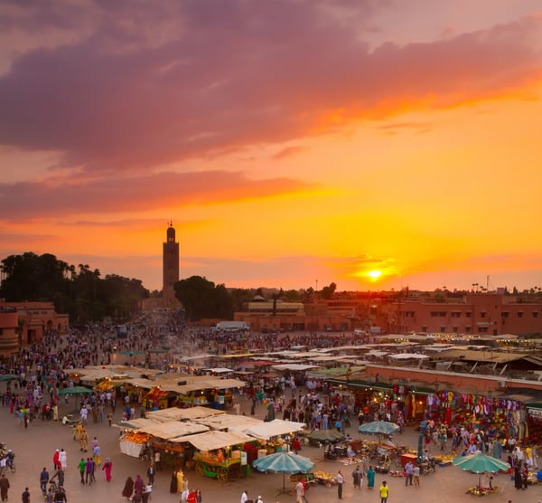 Djemaa el Fna Platz in Marrakesch bei Sonnenuntergang mit Marktständen Menschenmenge und Minarett