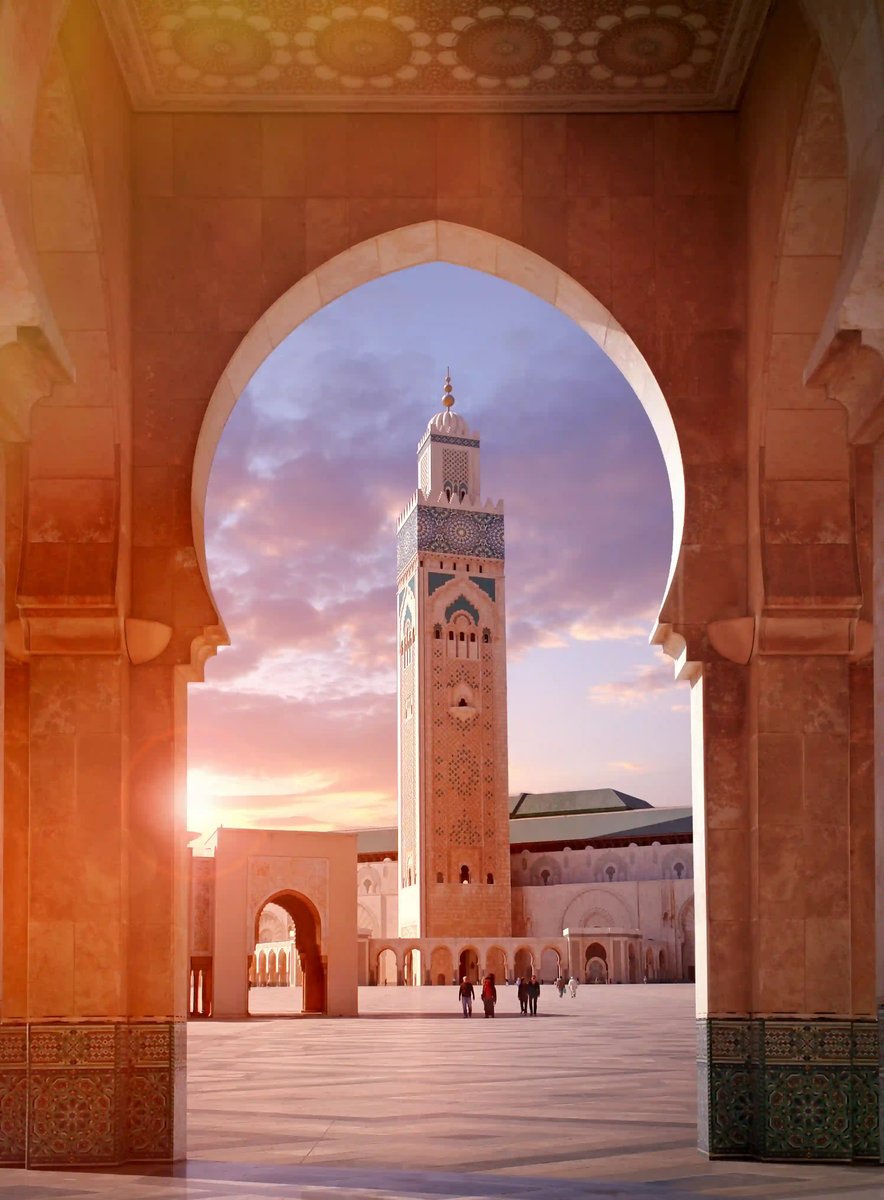 Hassan II Moschee in Casablanca durch einen Torbogen gesehen mit hohem Minarett und weitem Innenhof