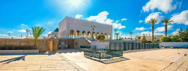 Mausoleum von Mohammed V in Rabat mit arkadierter Architektur Palmen und hellem Steinplatz