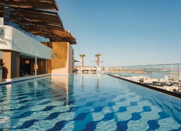Rooftop Pool eines Hotels auf Malta mit Liegen, Palmen und Blick auf das Meer