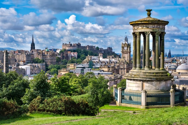 Blick auf Edinburgh mit Burg und historischem Stadtbild sowie einem Denkmal im Vordergrund