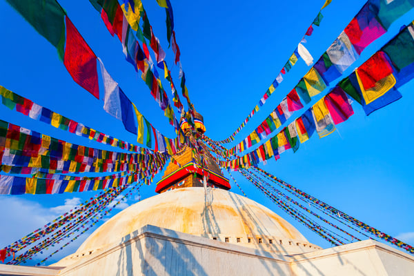 Boudhanath Stupa in Kathmandu mit bunten Gebetsfahnen vor blauem Himmel