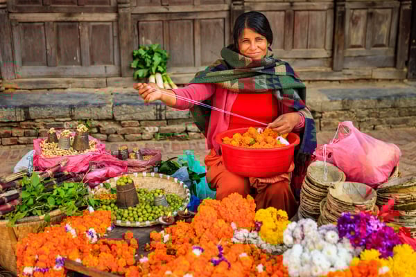 Frau verkauft Blumen und Lebensmittel auf einem Markt in Nepal