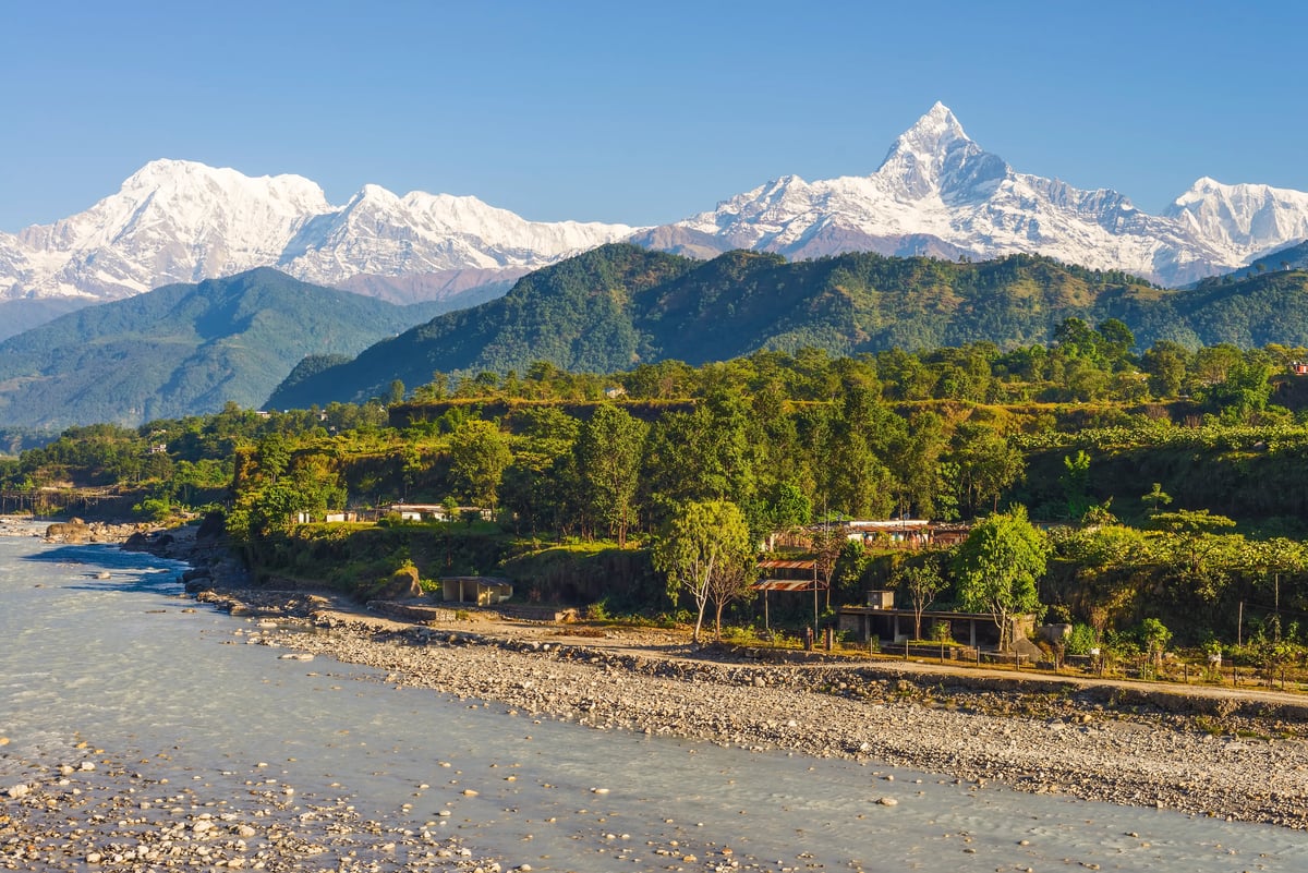 Blick auf die schneebedeckten Gipfel der Annapurna Kette über grüner Landschaft