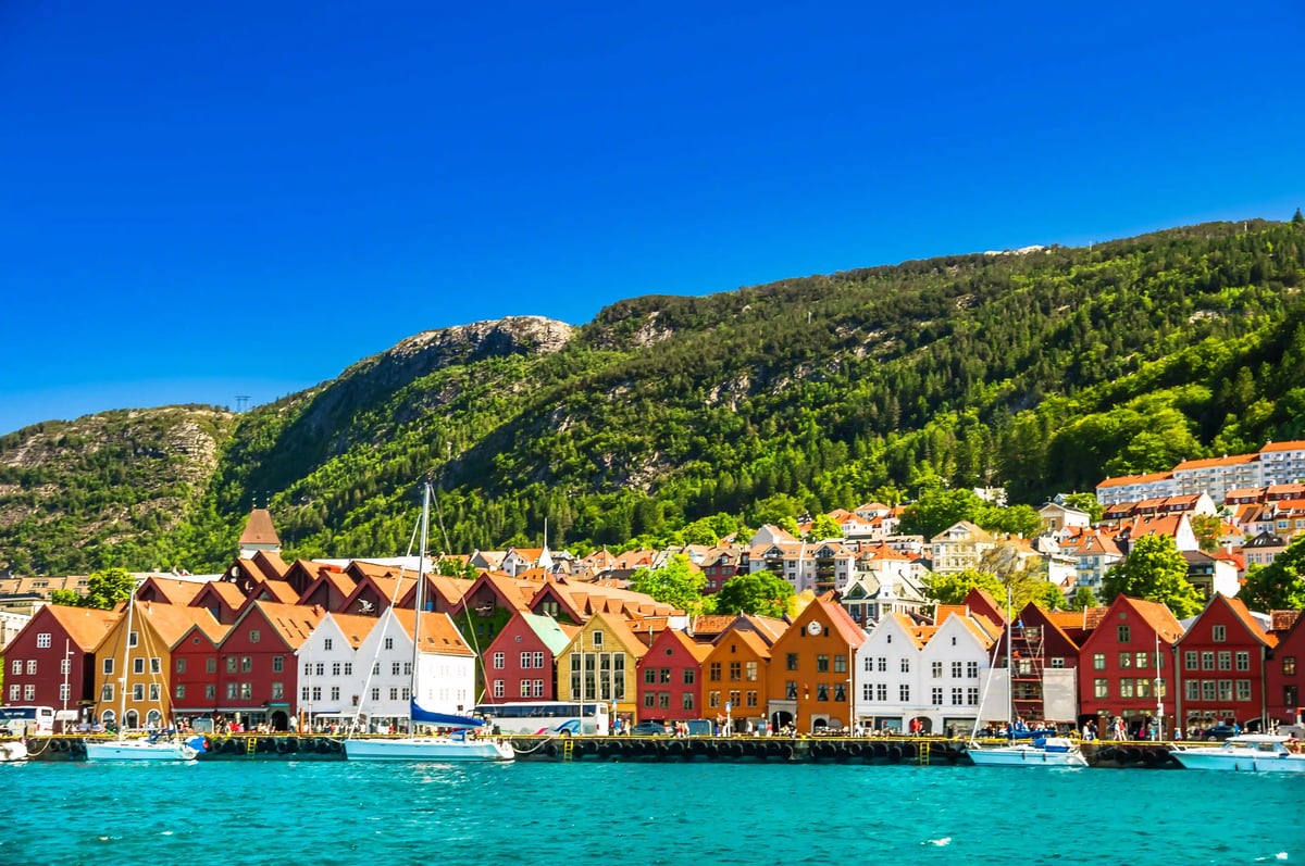 Bunte historische Holzhäuser von Bryggen im Hafen von Bergen vor bewaldeten Hügeln