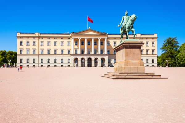 Königliches Schloss in Oslo mit Reiterstatue auf dem Vorplatz unter blauem Himmel