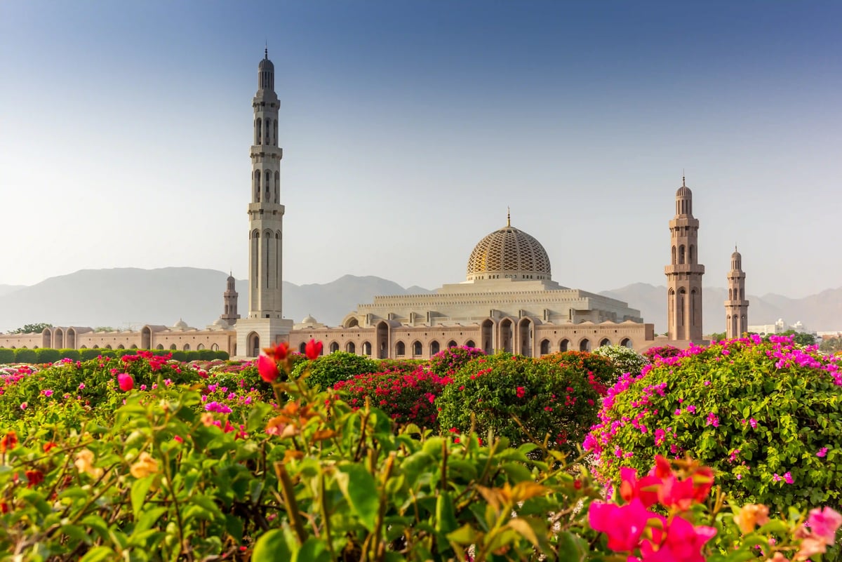 Sultan-Qaboos-Moschee in Muscat mit grosser Kuppel, Minaretten und blühenden Gärten im Vordergrund