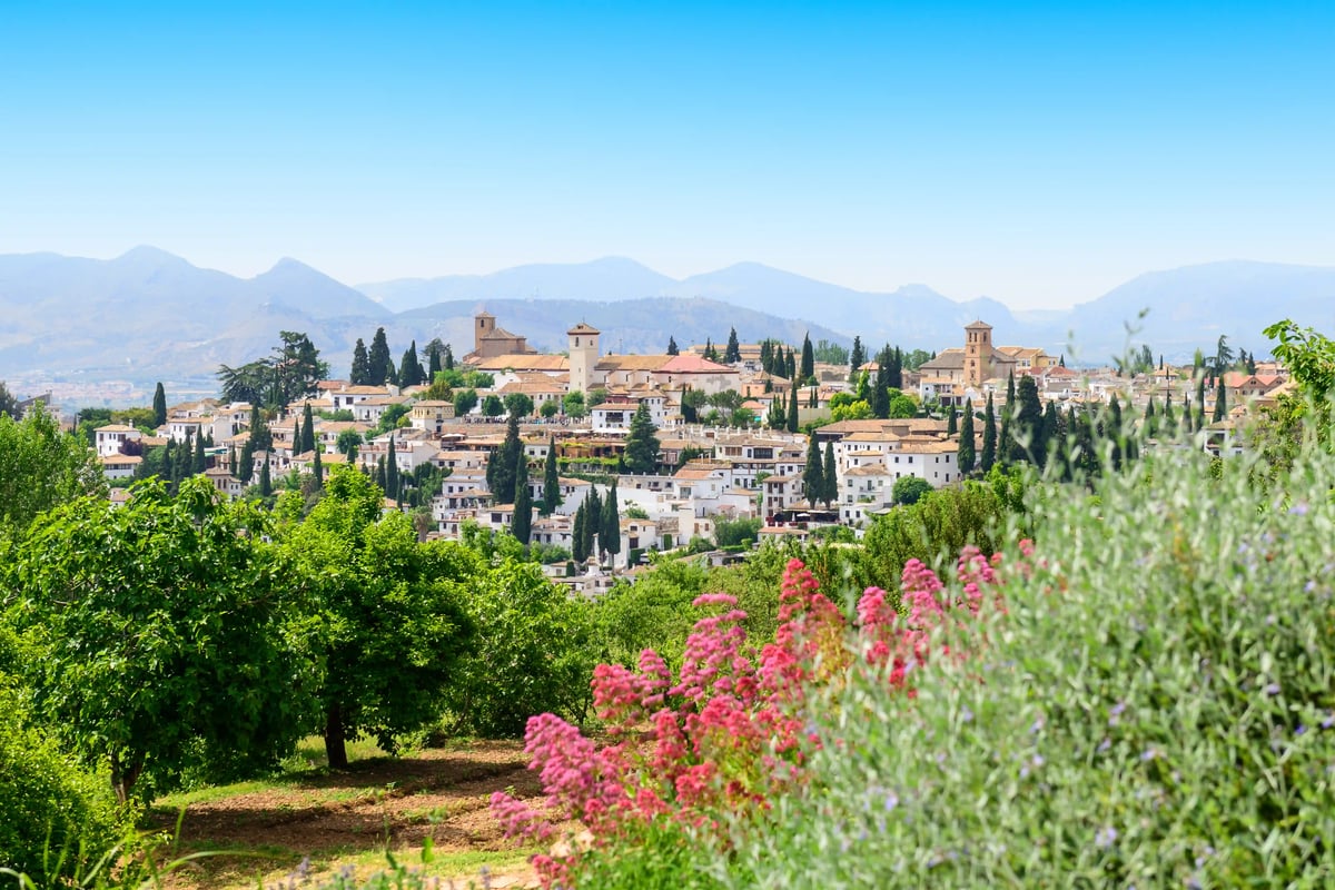 Andalusisches Dorf mit weissen Häusern, Zypressen, grünen Hügeln und blühenden Pflanzen
