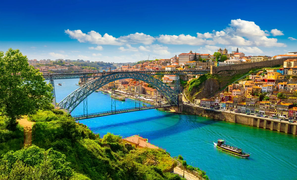 Panorama der Brücke Dom Luís I über den Douro mit bunten Häusern am Ufer und Boot auf dem Wasser