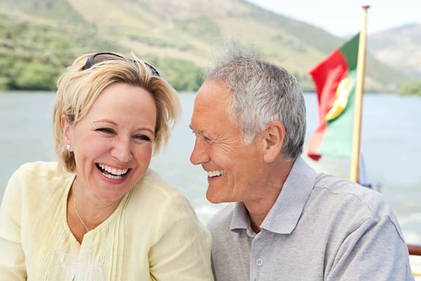 Couple riant sur un bateau, avec paysage fluvial en arriere plan et drapeau portugais au vent