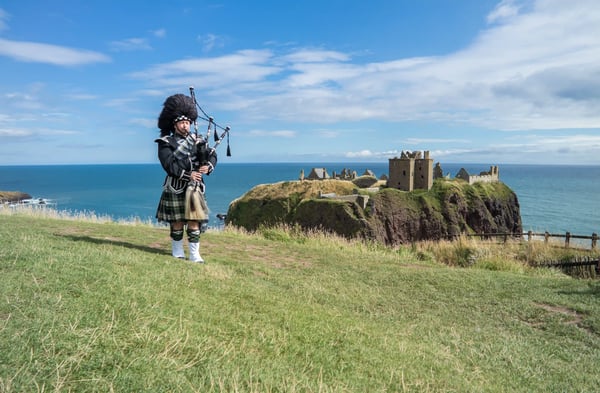 Dudelsackspieler vor Kueste und Burgruine