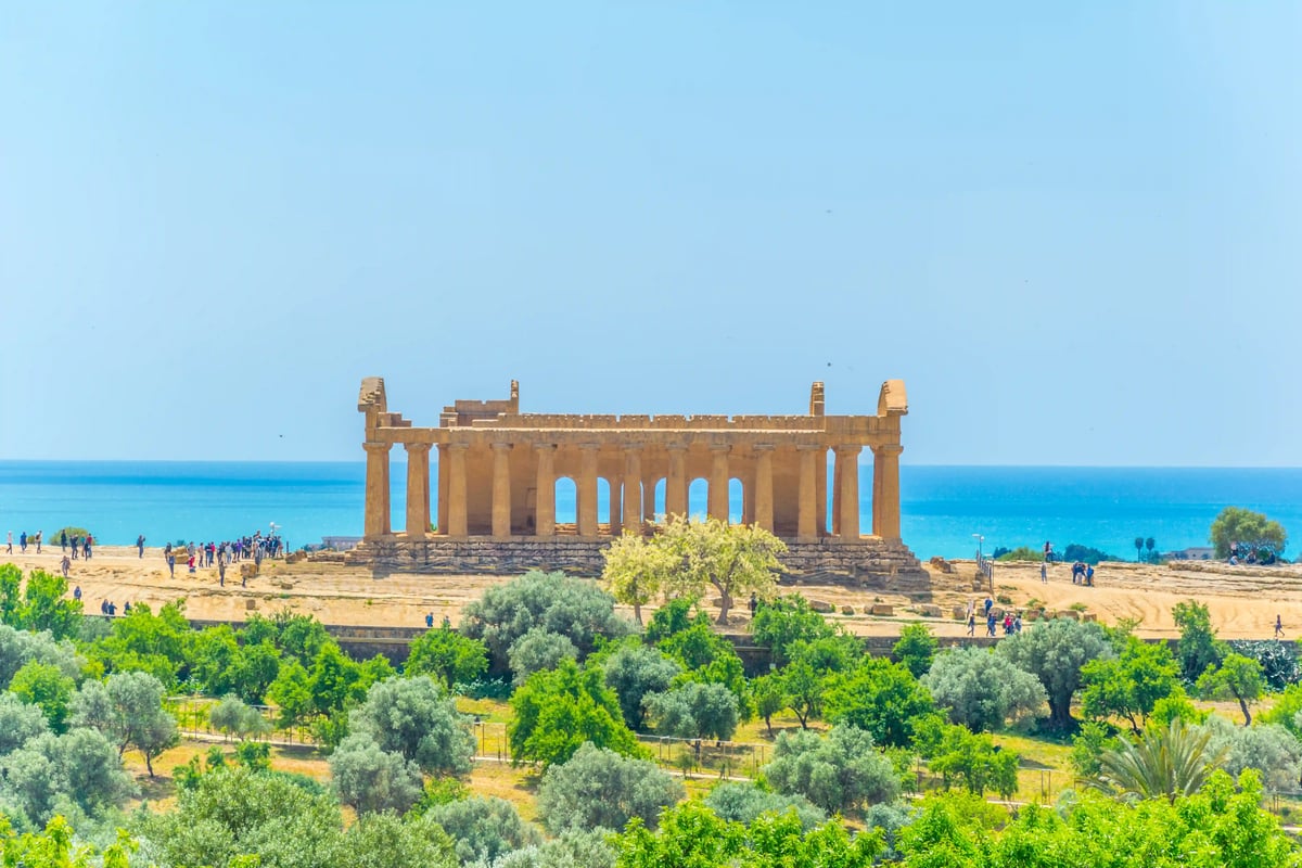 Antiker griechischer Tempel mit erhaltenen Säulen in weiter Landschaft nahe dem Meer