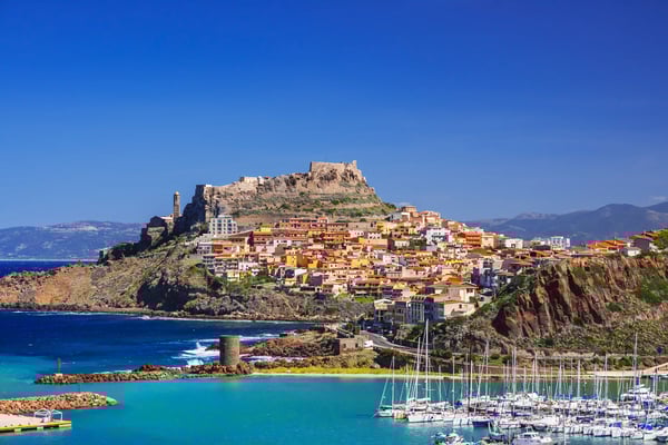Blick auf Castelsardo mit bunten Häusern, Burganlage und Hafen am Meer