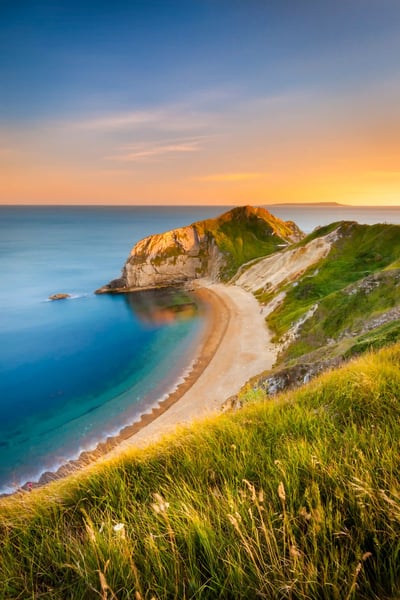 Küstenlandschaft bei Durdle Door mit natürlichem Felsbogen, Sandstrand und blauem Meer