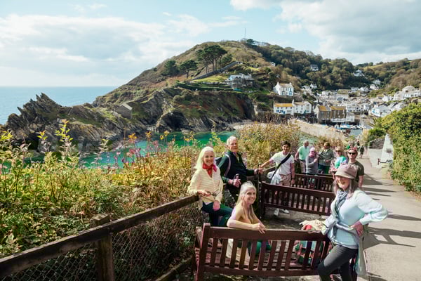 Reisegruppe steht auf einem Aussichtspunkt mit Blick auf Hafen, Küstenort und Felslandschaft